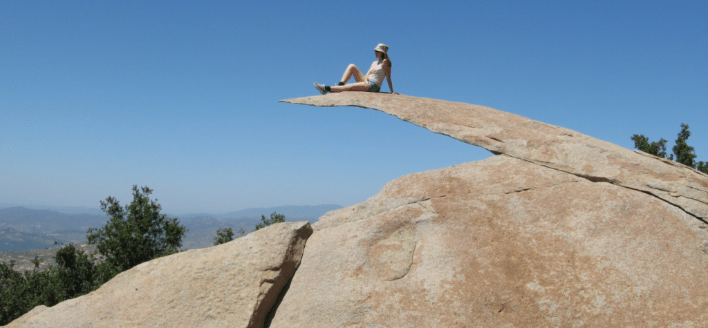 photo of woman sitting on potato chip rock showing one of the best san diego hikes and trails