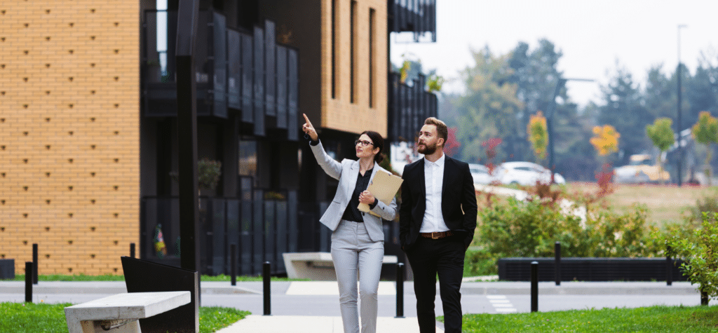 photo of man and woman looking at an investment commercial property showing how to create wealth investing in real estate